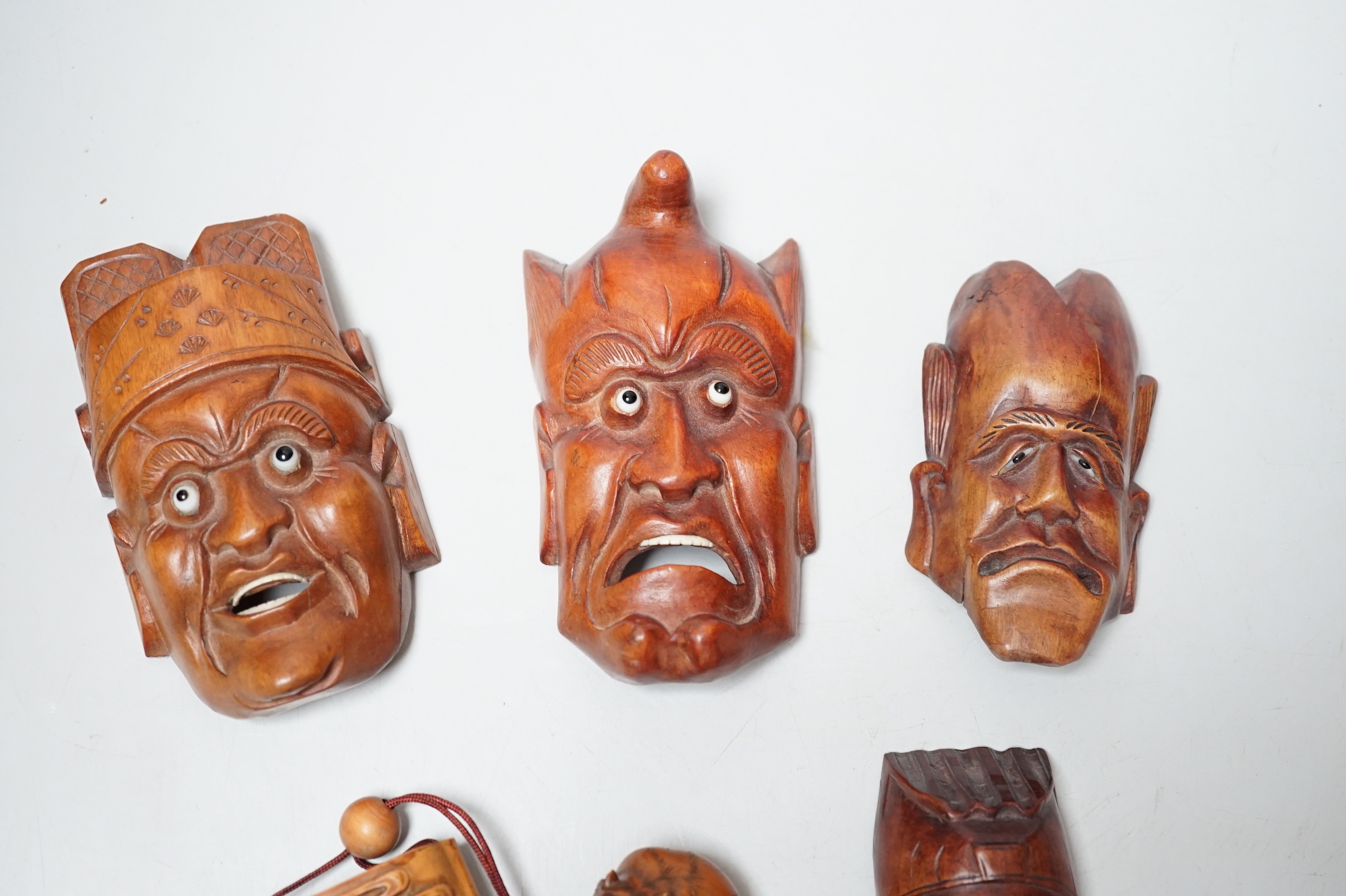 A group of hardwood models of noh masks and a similar inro, 9cm and netsuke